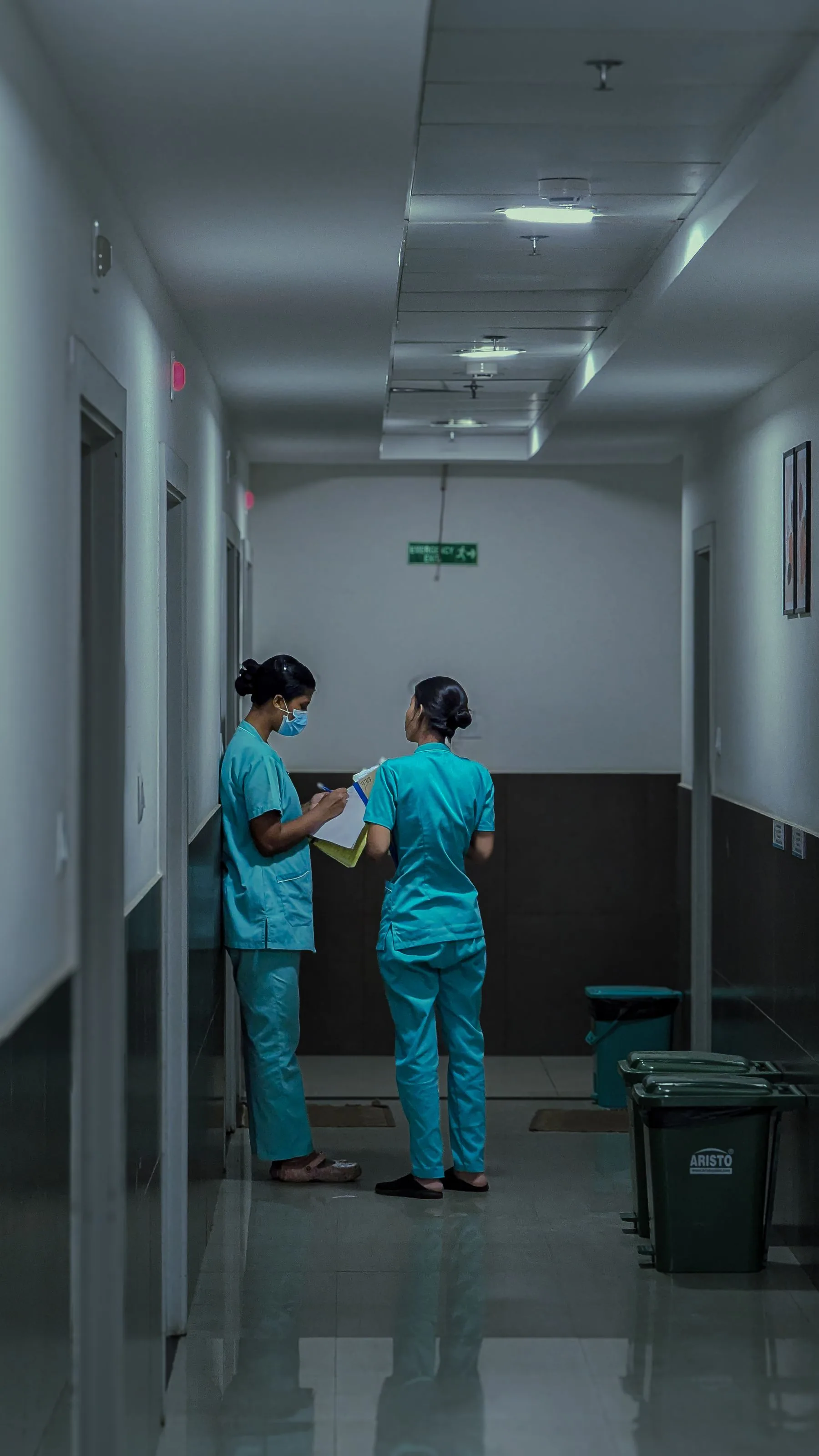Two nurses discussing patient notes in a hospital corridor