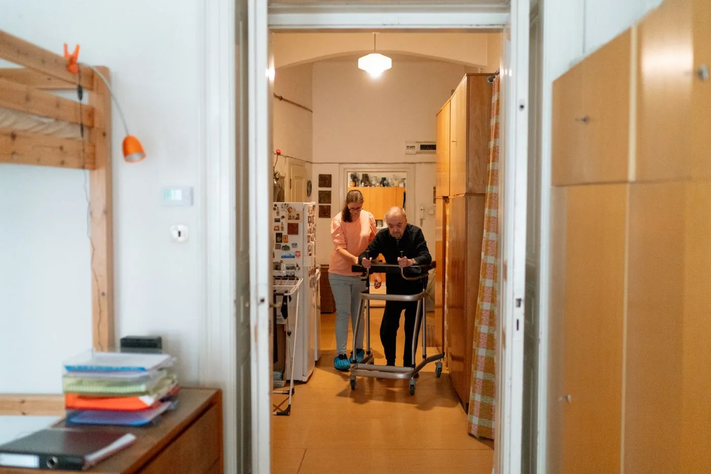 A caregiver helping an older man use a walking frame at home